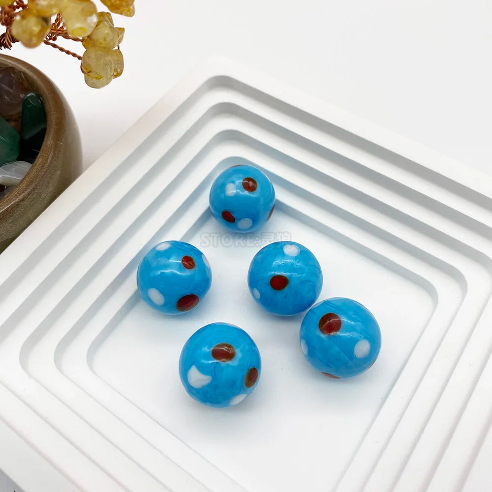 Perles de verre bleues avec des points rouges arrangées sur un plateau blanc