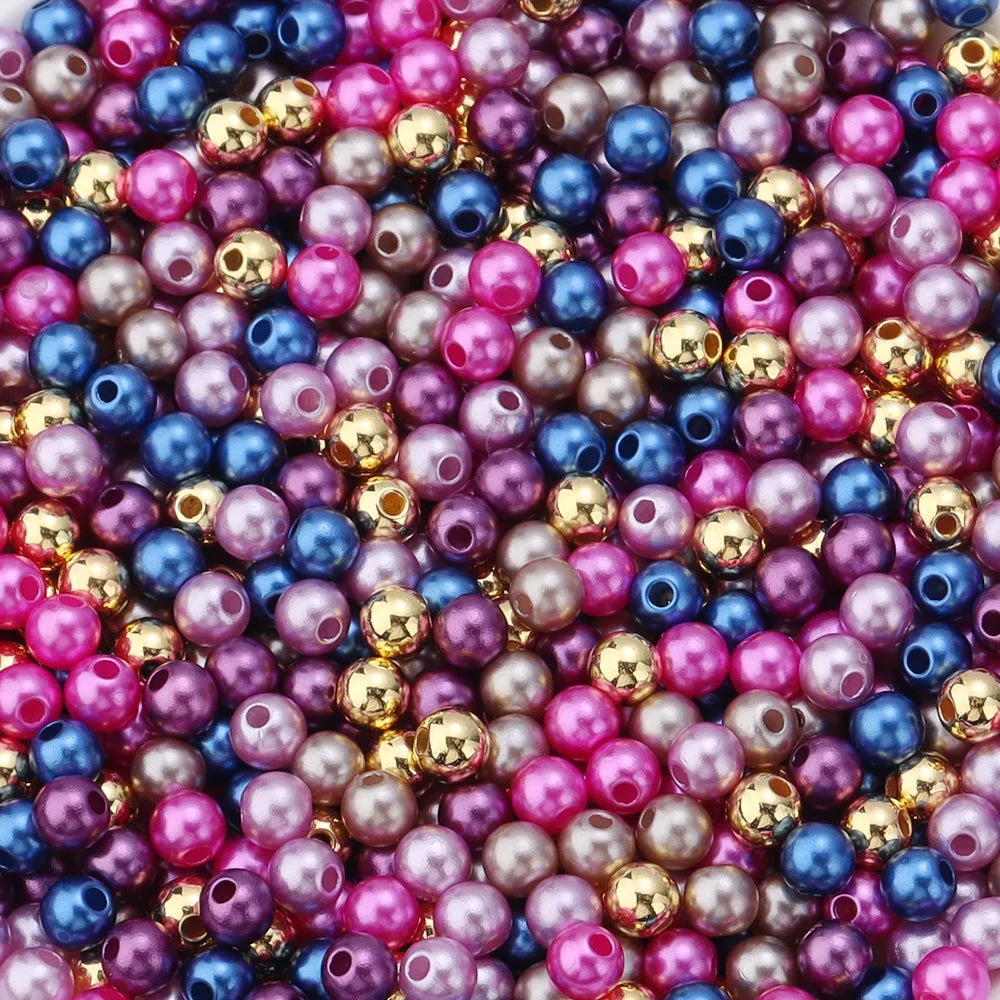 A close-up of colorful imitation pearl beads in various shades of pink, purple, blue, and gold.