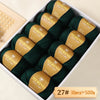 A box of dark green Merino wool yarn balls with yellow labels, packaged for knitting projects.