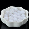 A white ceramic dish filled with small, round, white acrylic pearl beads for jewelry making.