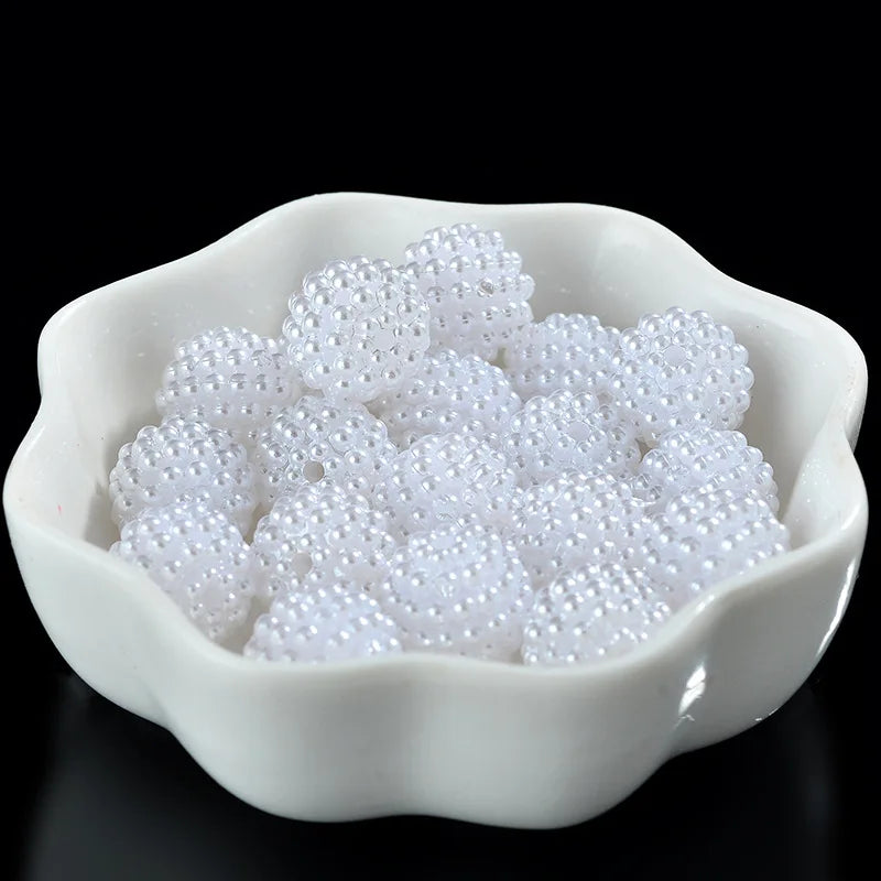 A white ceramic dish filled with small, round, white acrylic pearl beads for jewelry making.