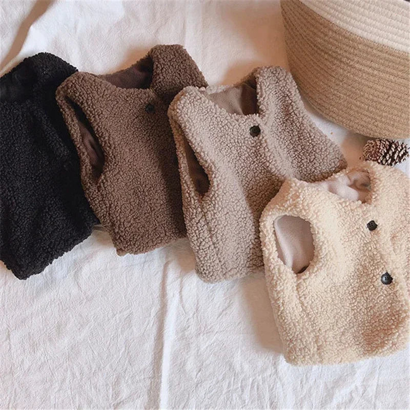 A collection of beige and brown lamb wool vests for children displayed on a white surface.
