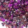 A close-up view of various faceted crystal bicone glass beads in shades of purple, pink, and amethyst.