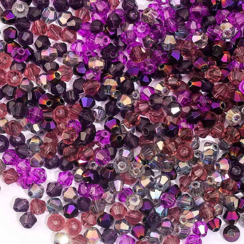 A close-up view of various faceted crystal bicone glass beads in shades of purple, pink, and amethyst.