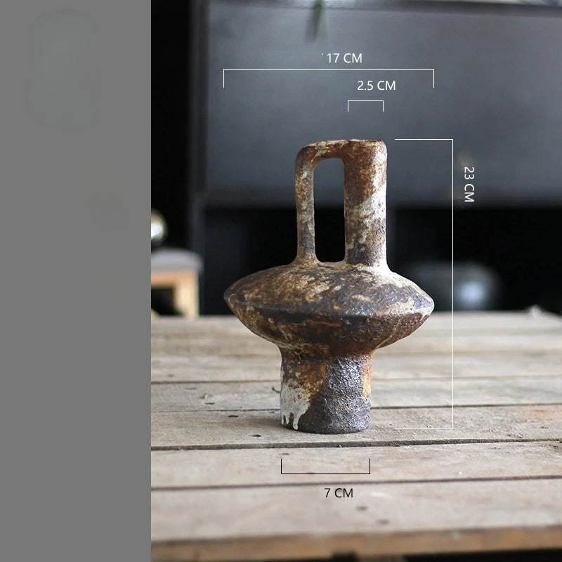 A vintage handcrafted ceramic vase with an elongated spout and a flared base, shown on a wooden surface.