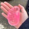 A hand holds a translucent pink moldable squishy stress relief toy shaped like a foot.