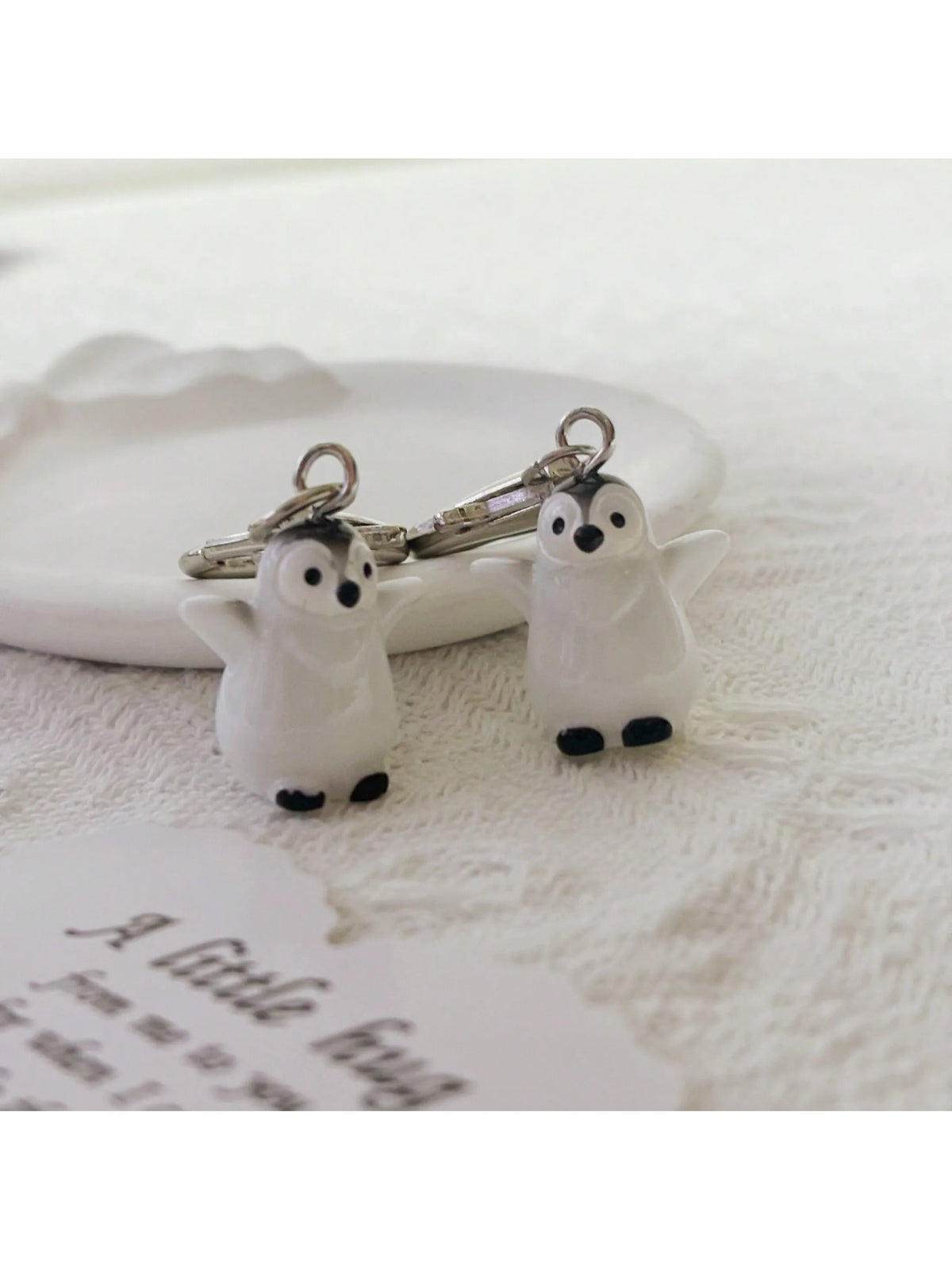 A silver heart keychain set featuring two small white penguin charms.