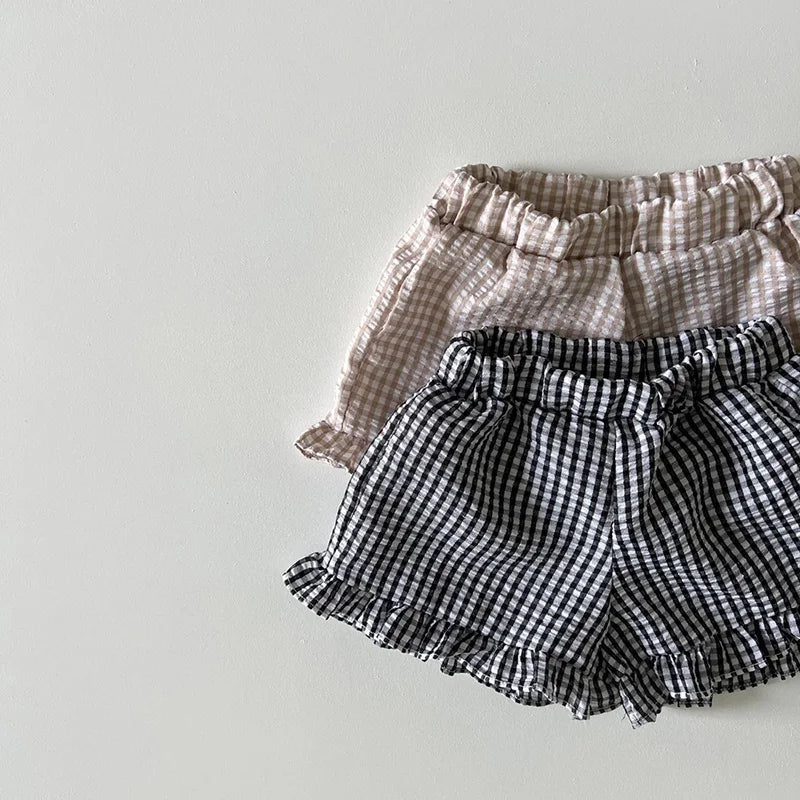 A set of light beige and black checkered ruffle top and shorts for a baby girl summer outfit.