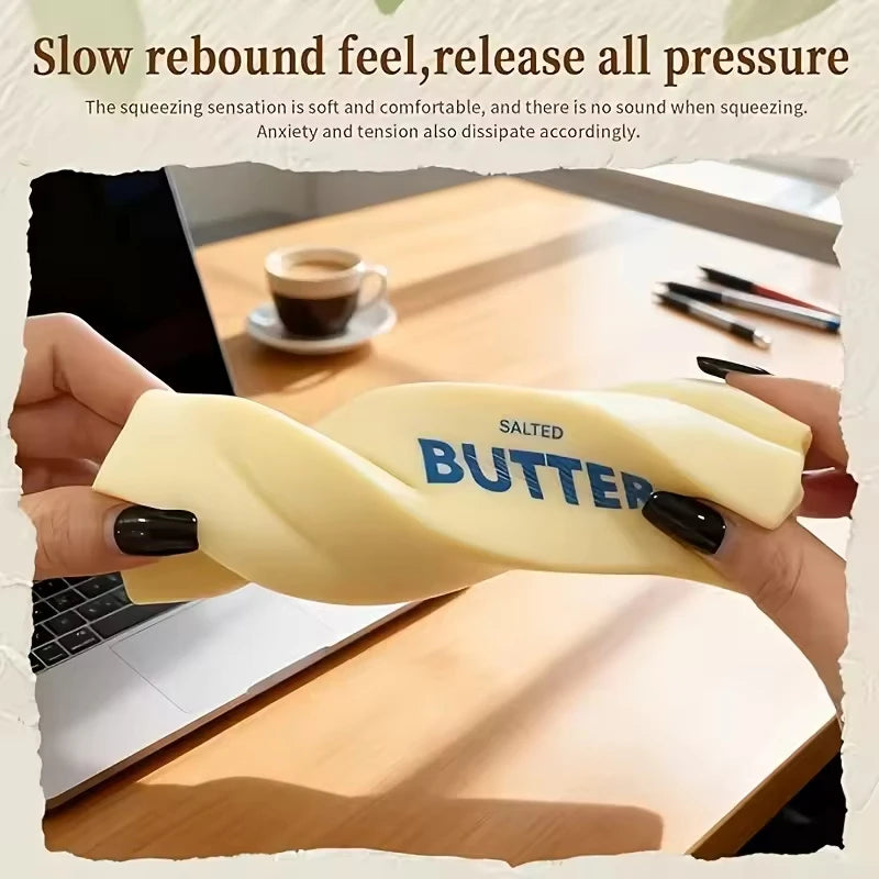 A hand holds a yellow butter squishy stress relief toy with the word salted butter visible on it.