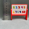 A red rectangular sign with colorful numbers 1 through 10 is shown next to a ruler.