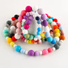 A loose strand of colorful silicone beads in various sizes and shades arranged in a circular pattern.