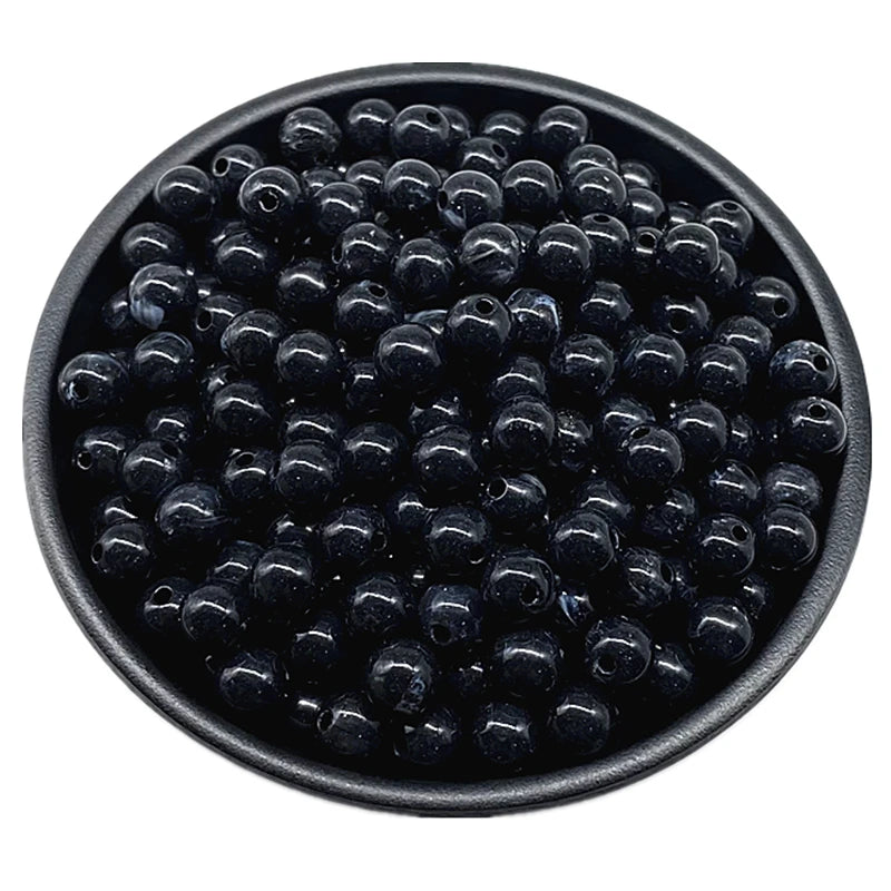 A black bowl filled with small, round acrylic beads for jewelry making.
