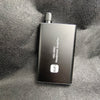 A black portable HiFi headphone amplifier with a silver cap is shown against a dark gray textured background.
