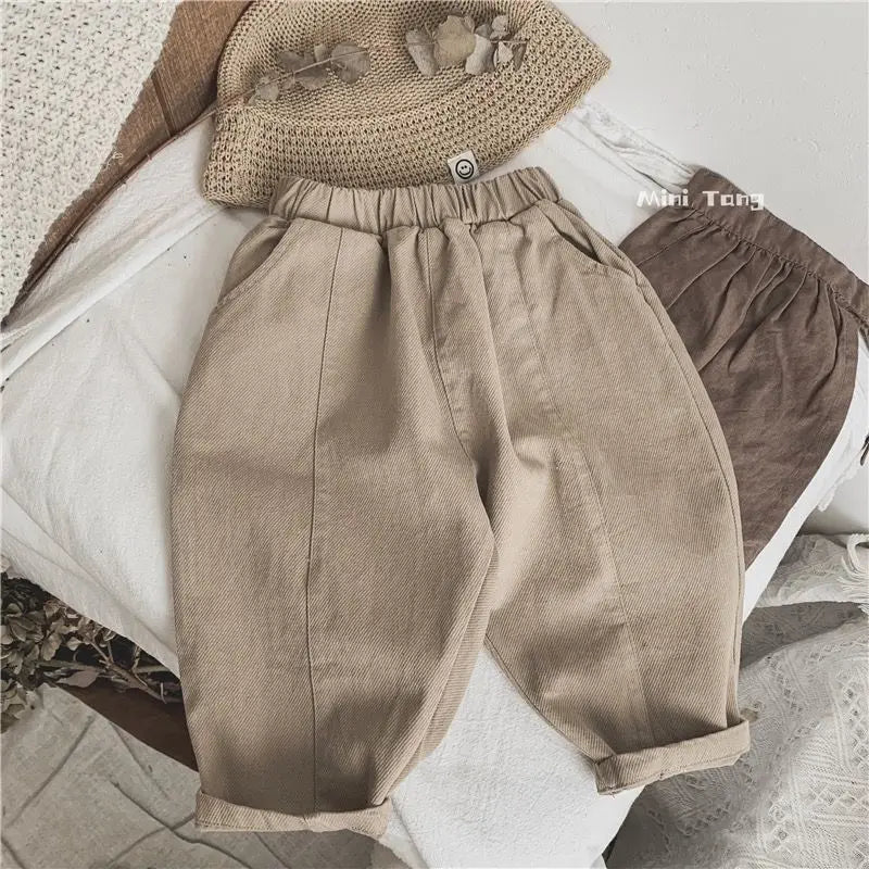 Tan loose wide-leg harem pants for boys displayed on a white surface.