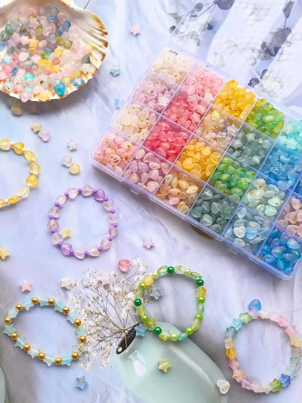 A collection of colorful frosted golden foil acrylic beads and jewelry making supplies arranged on white fabric.