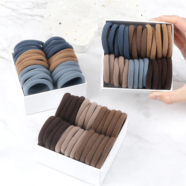 A collection of 50 elastic hair bands in various shades of brown and gray are displayed in white packaging.