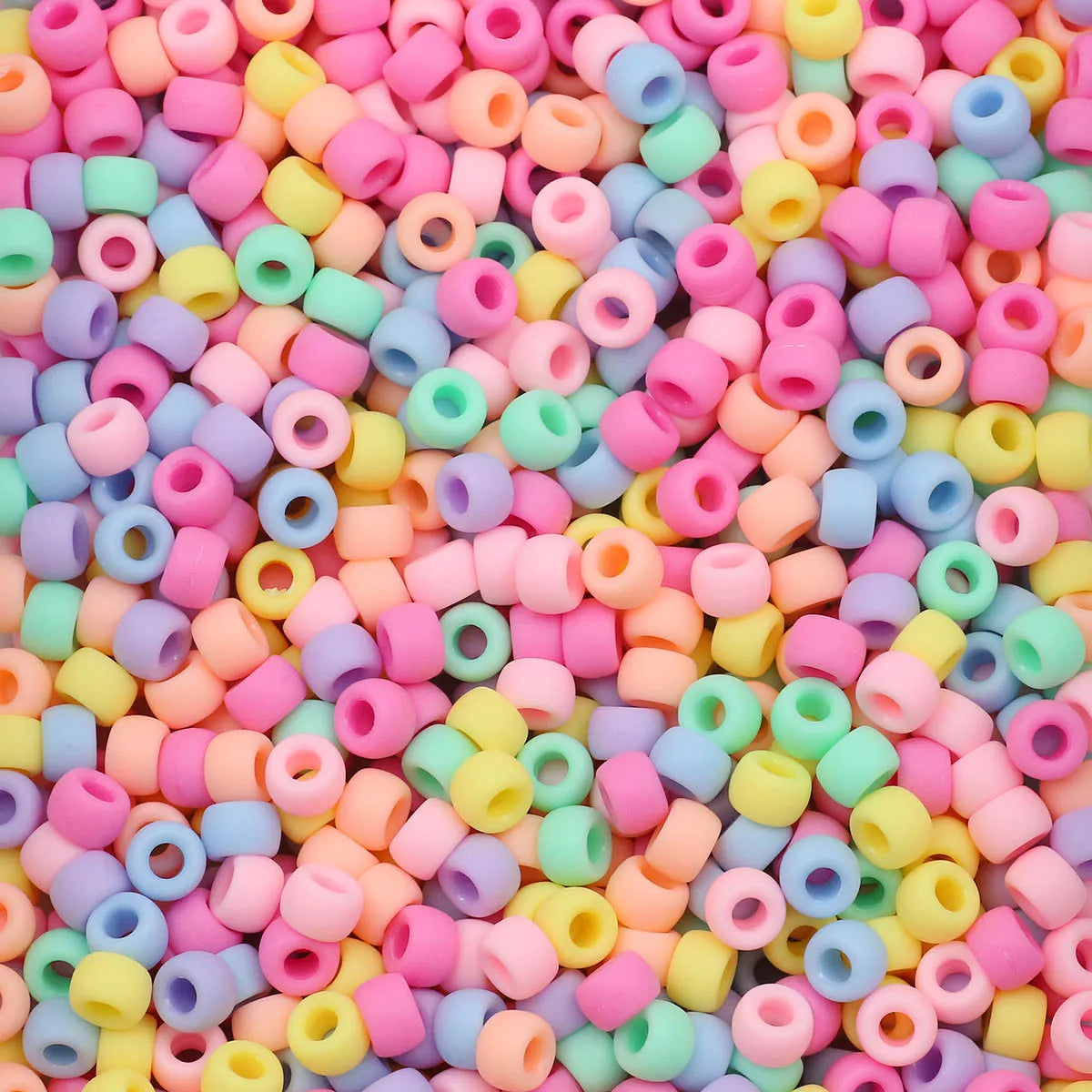 A close-up view of a large pile of multicolor pony beads in various shades of pink, yellow, blue, and green.