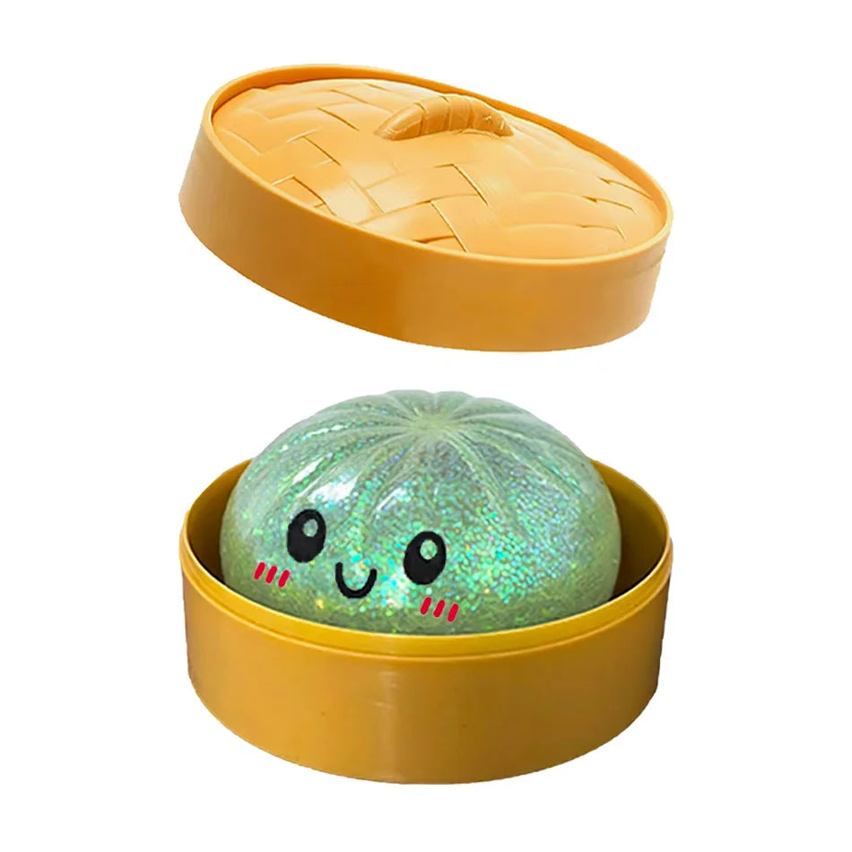 A yellow plastic container holds a translucent, glittery green squishy toy shaped like a dumpling.