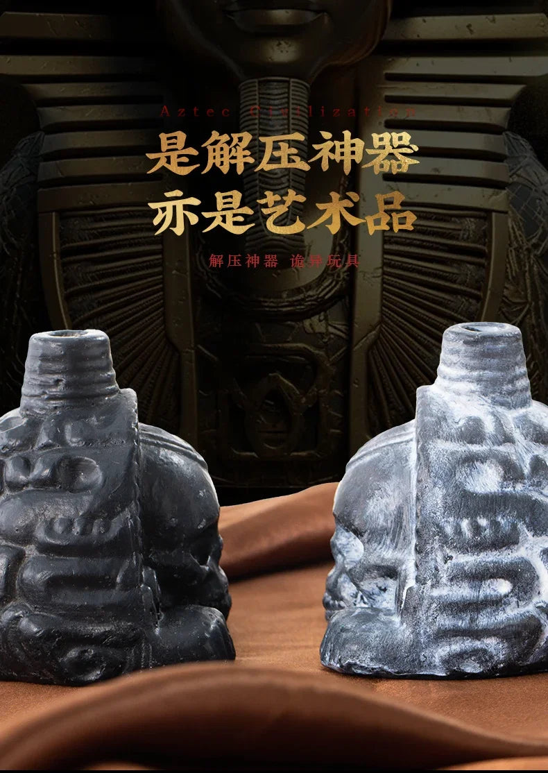 Two handcrafted Aztec death whistles in dark gray and light gray stone are displayed against a dark background.