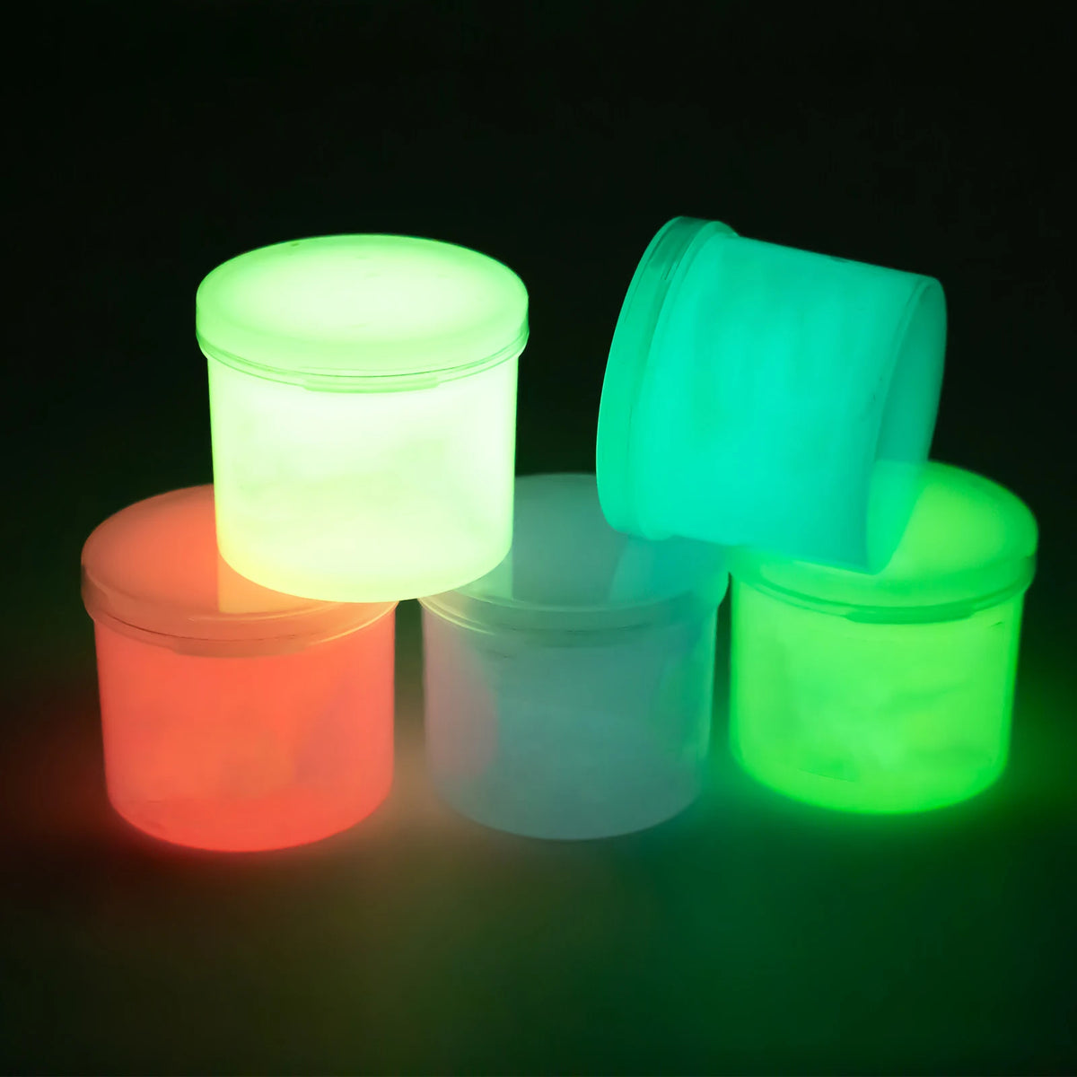 Four small plastic containers of glow-in-the-dark slime in various colors including green, yellow, orange, and pink.