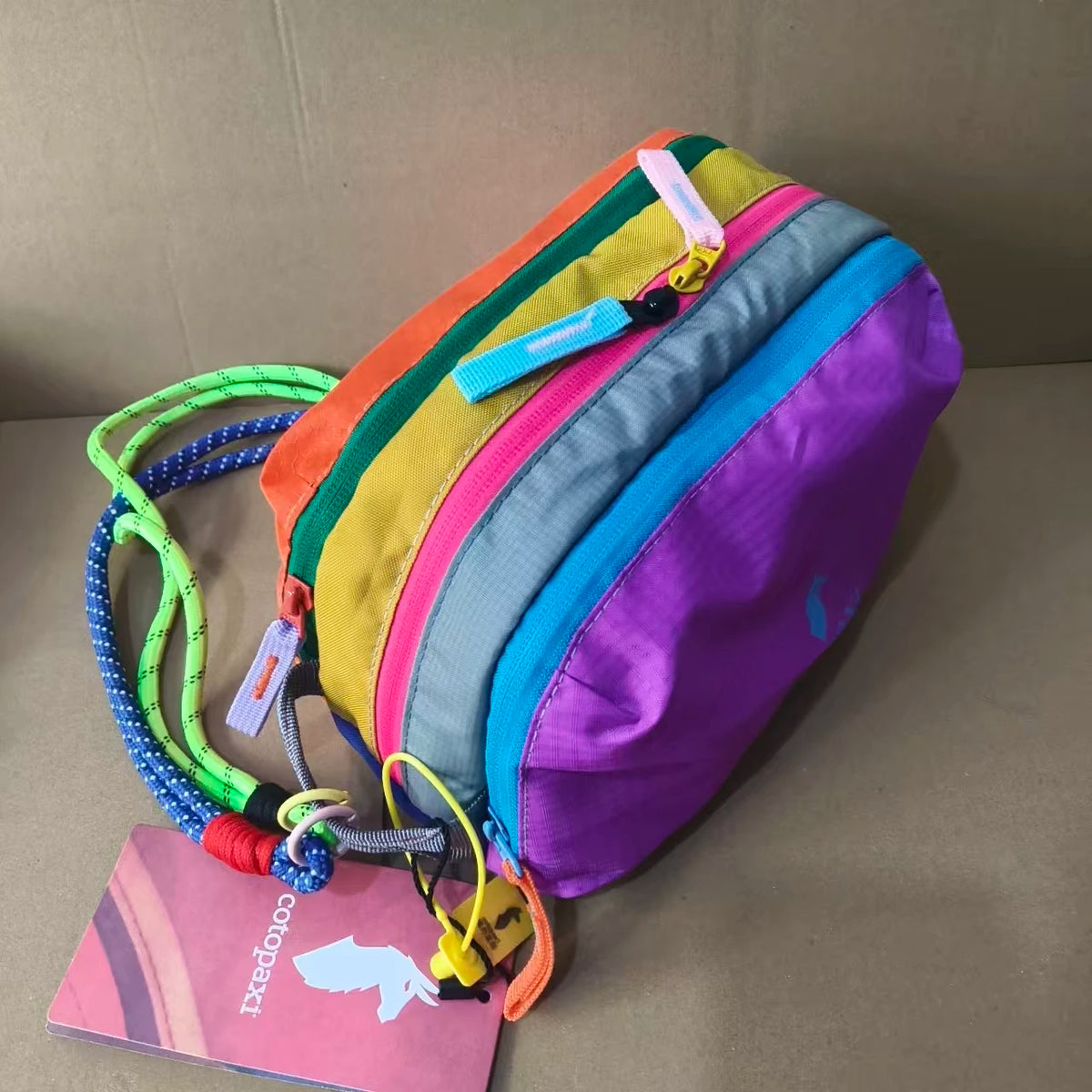 A purple and multicolored alpaca themed travel storage bag with three zippered compartments.