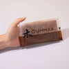 A hand holds a small plastic package of OUMMAA wood clay for sculpting.