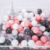 A white plastic basket filled with a bulk set of colorful clear and opaque ocean ball pit toys.