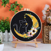 Embroidery kit featuring a black cat silhouette on a yellow crescent moon against a dark background