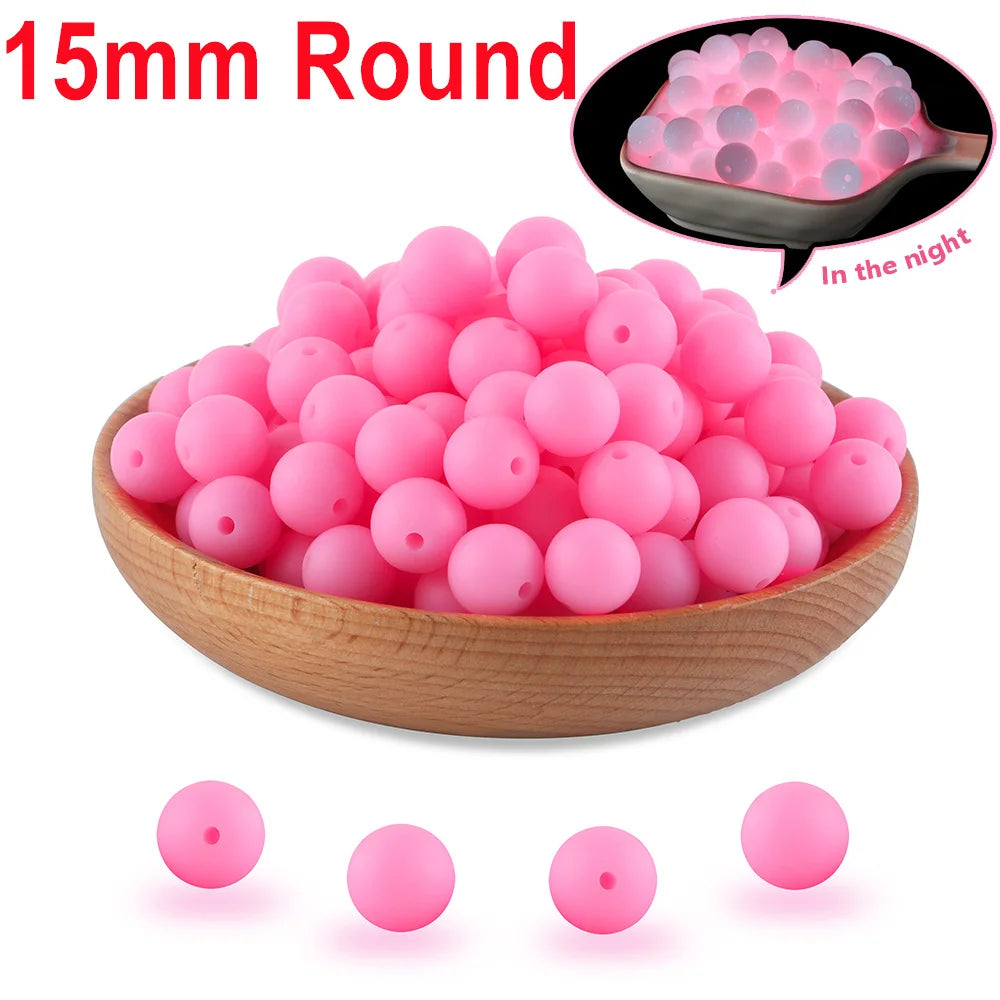 A bowl filled with pink silicone beads, 15mm round, used for glow in the dark DIY jewelry.