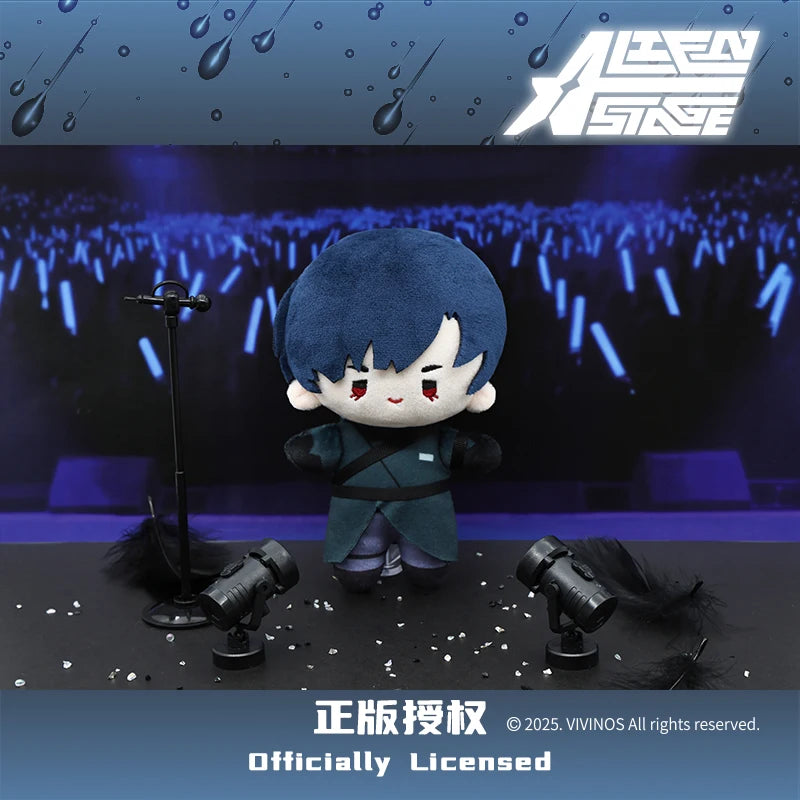 A dark blue plush doll resembling a character from Alien Stage is displayed on a stage with microphones and camera equipment.