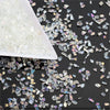 White crushed glass crystals mixed with iridescent pieces on a dark surface.