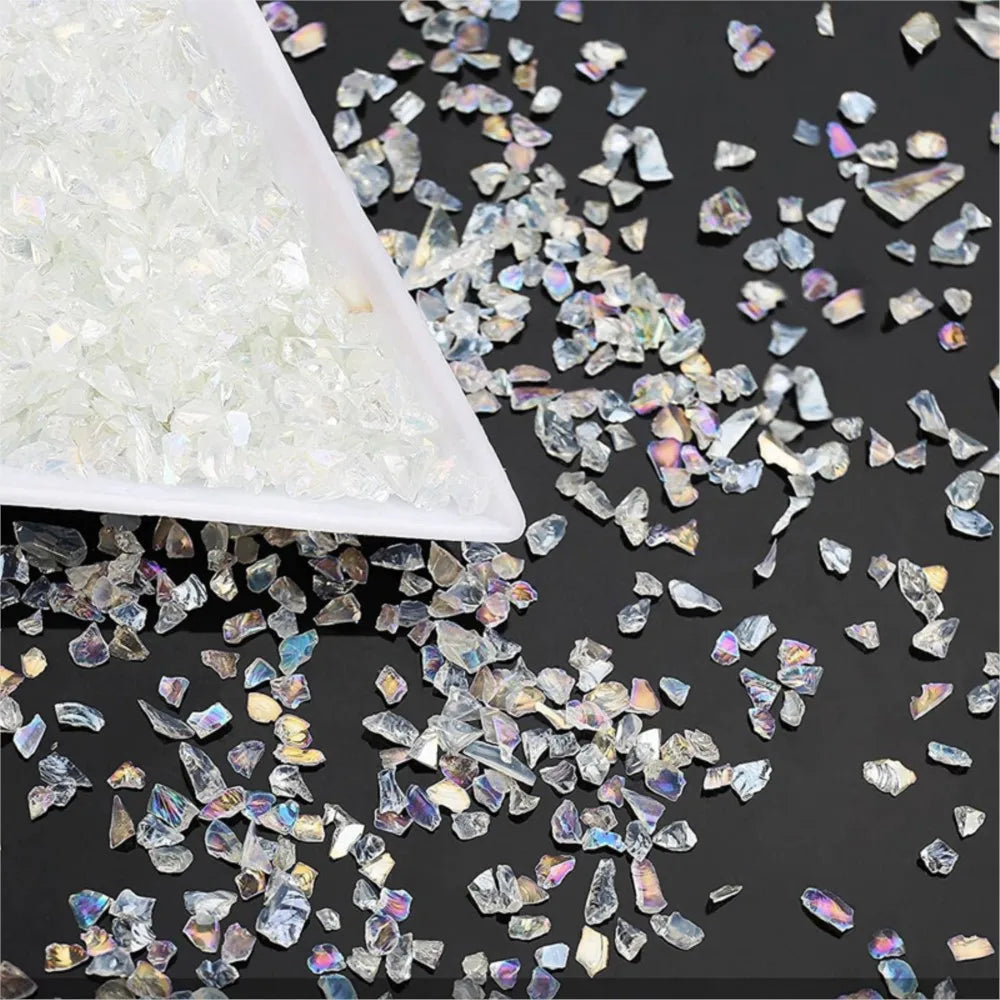 White crushed glass crystals mixed with iridescent pieces on a dark surface.