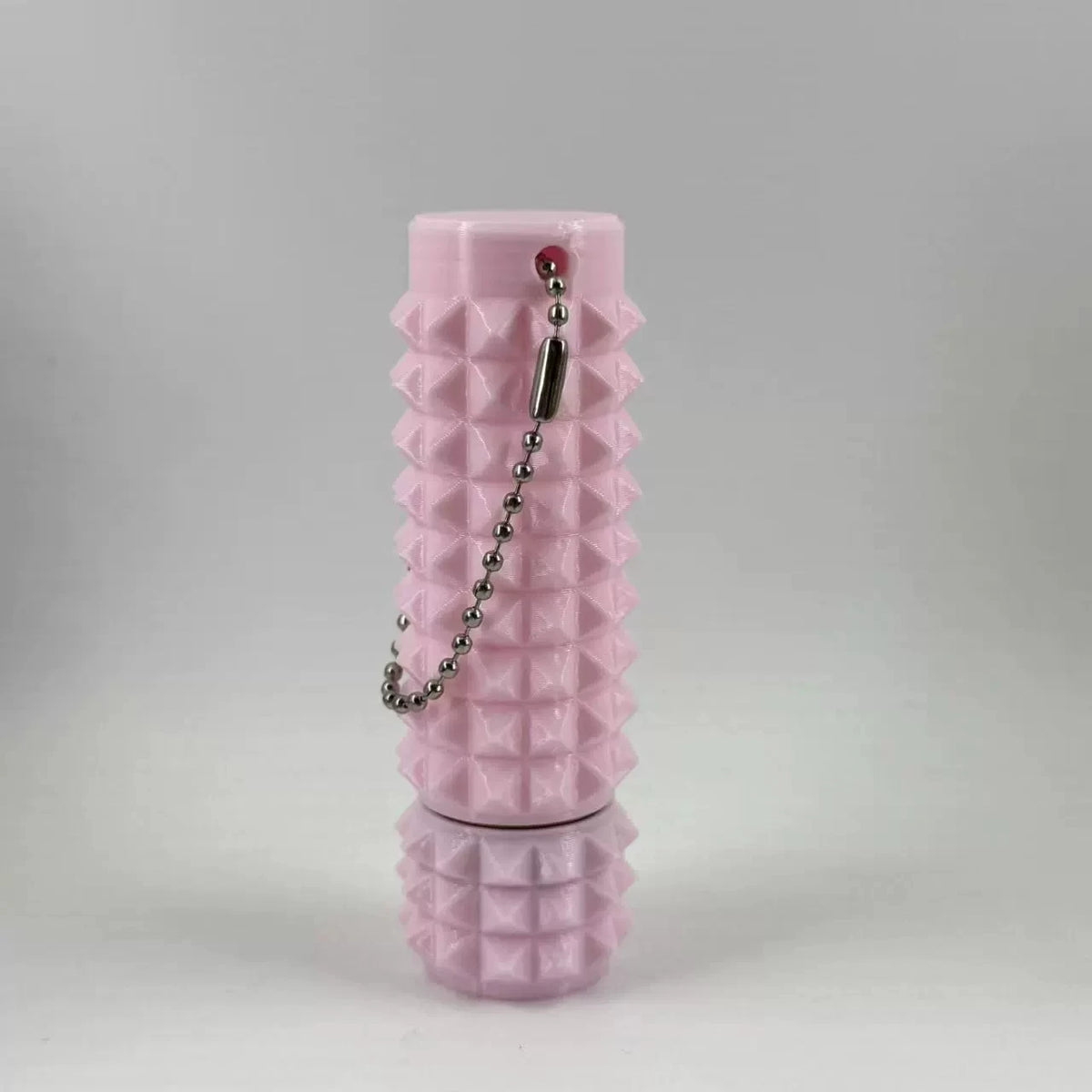 A pink, textured cylindrical fidget toy with a keychain attached.