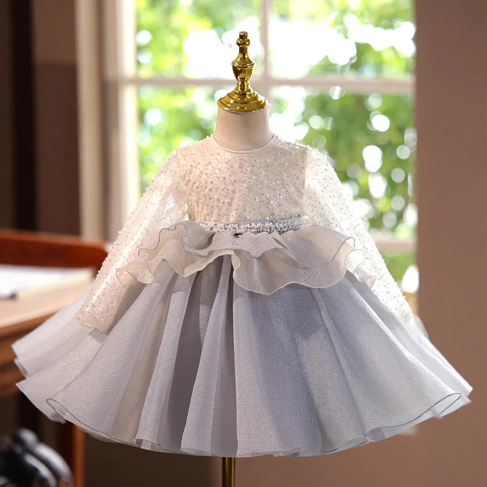A white and gray tulle princess dress displayed on a mannequin with a gold tiara.