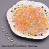 A pile of translucent orange and pink water drop Czech glass beads on a white plate.