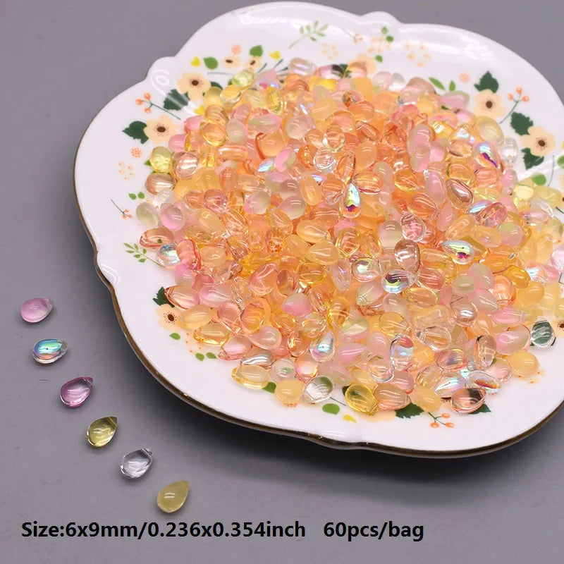 A pile of translucent orange and pink water drop Czech glass beads on a white plate.