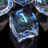 A close-up of a translucent blue resin dice set with seven polyhedral dice resting on a dark surface.