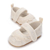 A pair of cream-colored lace-trimmed baby girl moccasin shoes with bows.