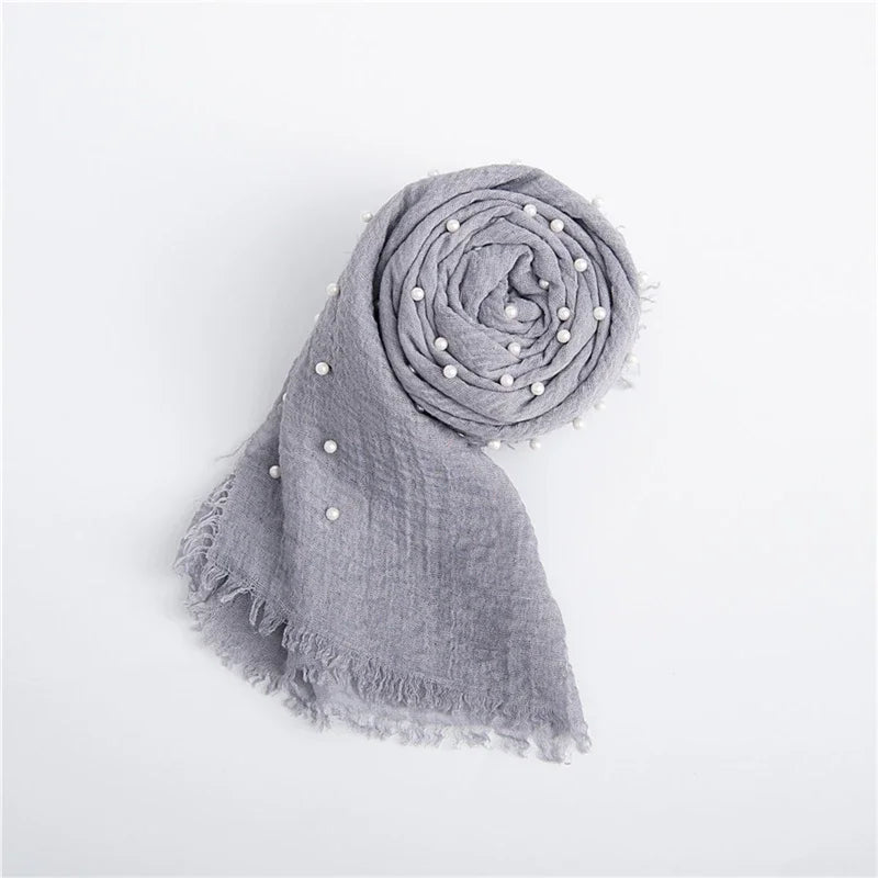 A gray knit wrap with a pearl headband, rolled into a spiral shape.