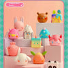 A collection of 12 water glow shades geometric monster mini bean blind box figures displayed on pink and white stands.