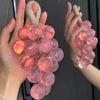 Hands hold a cluster of pink and orange silicone glass beads used for soap and candle making