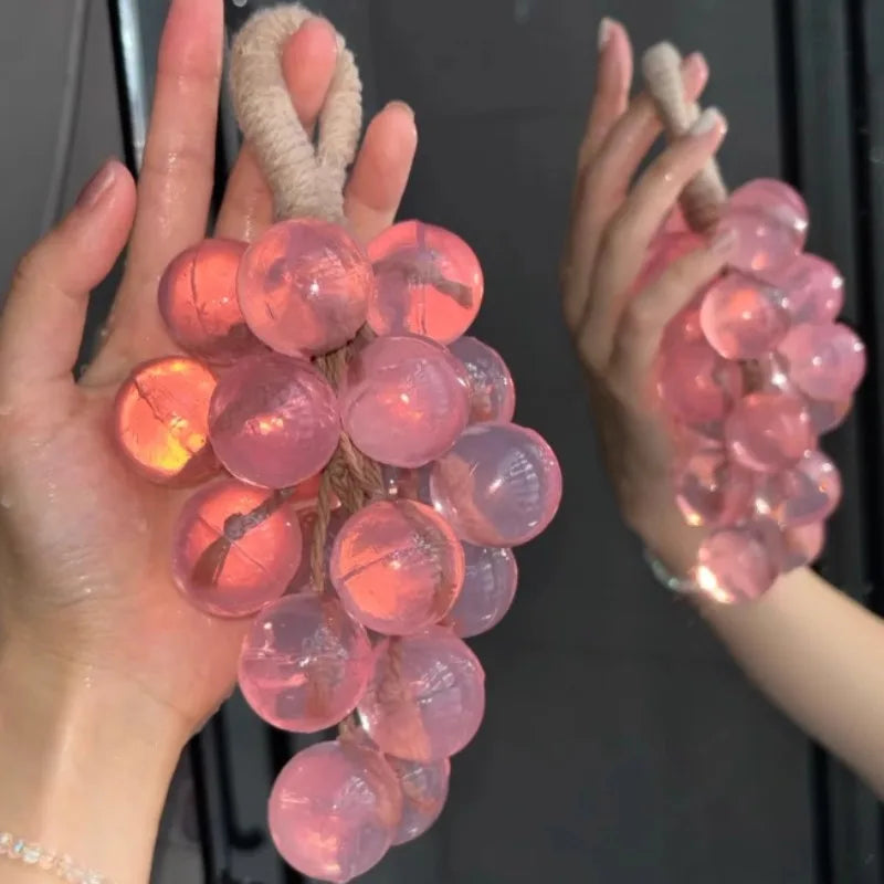 Hands hold a cluster of pink and orange silicone glass beads used for soap and candle making
