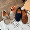 A pair of girls' brown slip-on moccasins with orange lining and bow details resting on a white cloth.