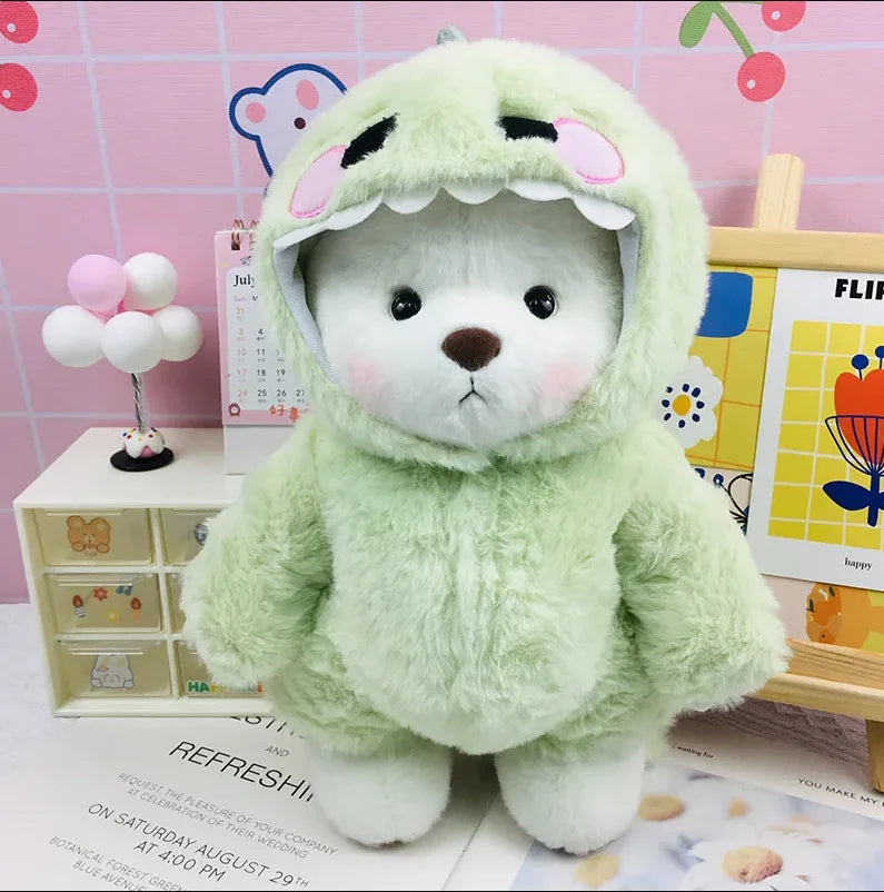 A light green plush doll with large ears and a hood is displayed on a wooden surface.