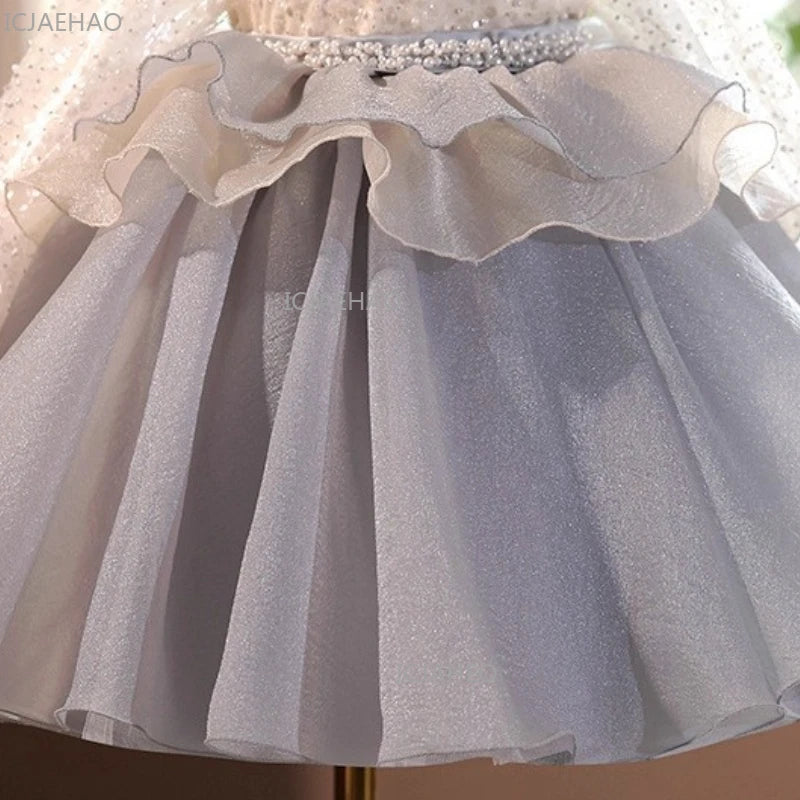 A light gray tulle dress for girls featuring ruffled layers and a pearl-encrusted waistband.