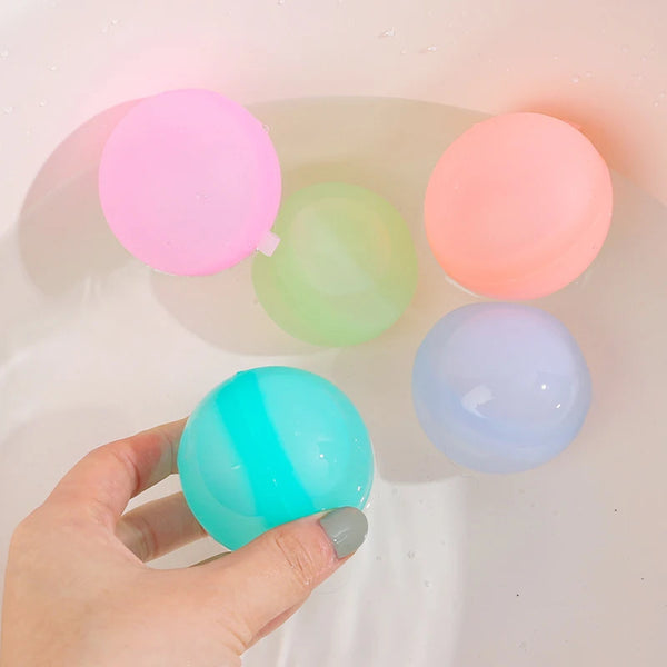 A hand holds a collection of colorful silicone water balloons floating in water.
