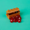 A wooden building block treasure chest set with gold and silver coins resting on a teal background.
