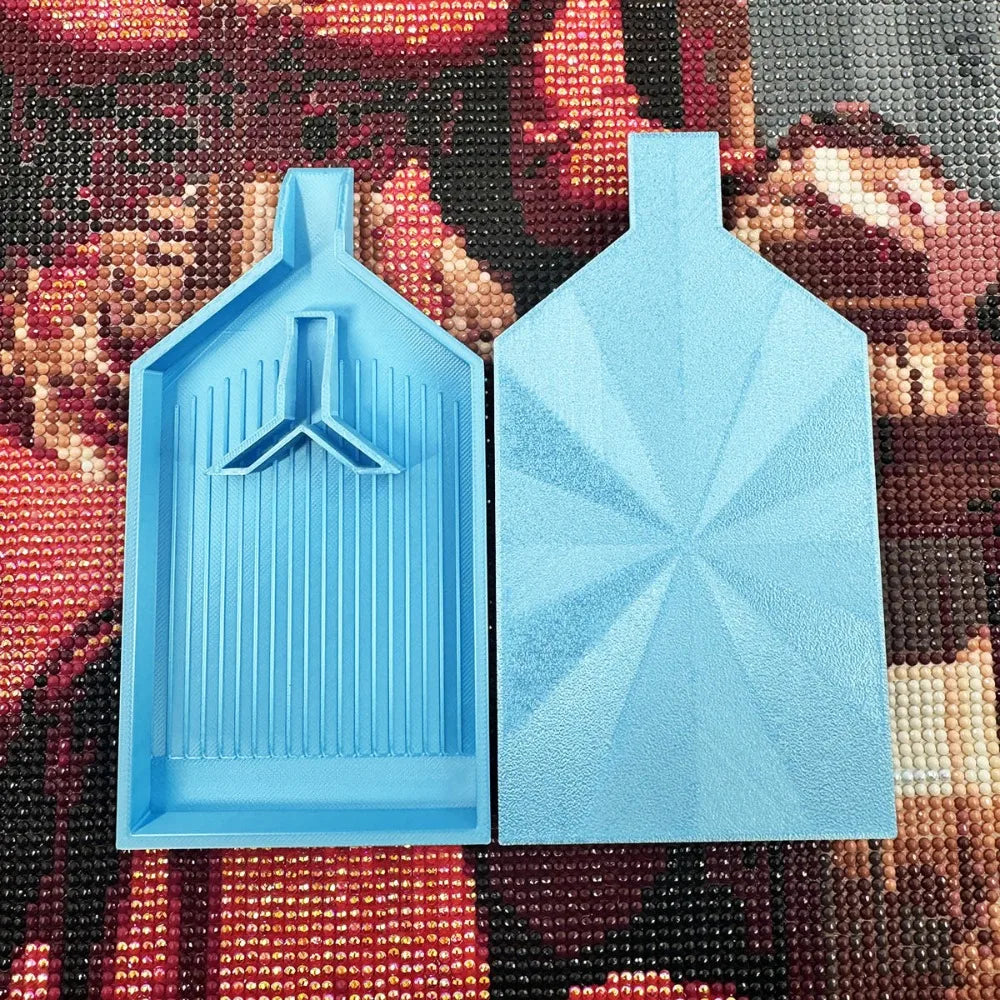 Two light blue diamond painting trays with pop-up plugs are displayed on a colorful fabric background.
