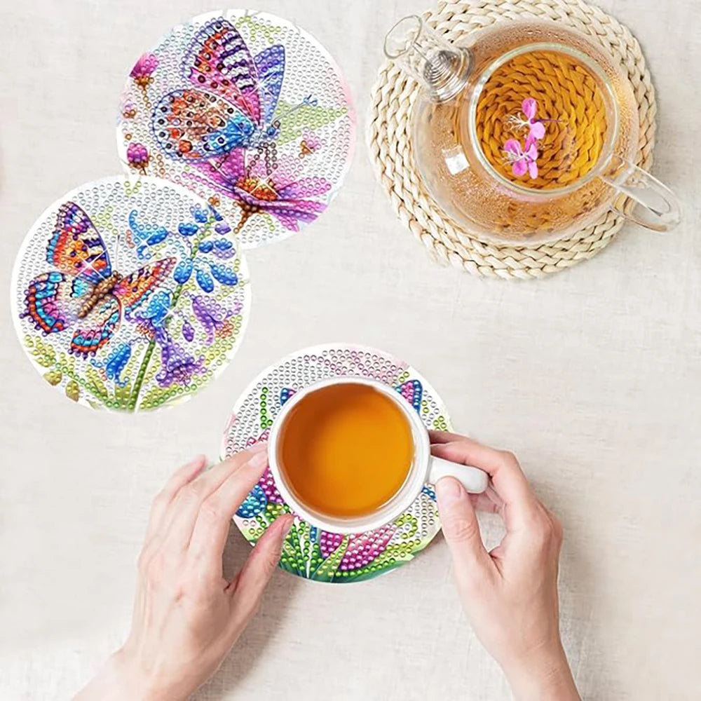 Hands hold a cup of tea next to a woven coaster and a colorful diamond art coaster