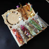 A wooden box containing a witchcraft starter kit with crystals and dried herbs, next to a decorative mirror.